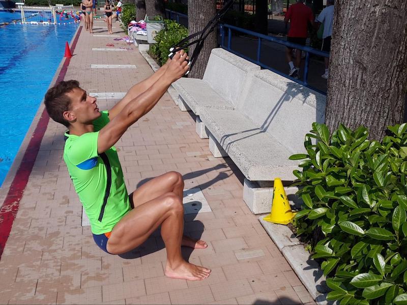 Navy SEAL swim workout: man doing squats using a TRX