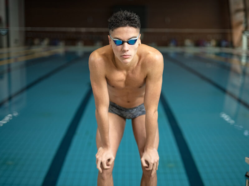 Swimmer wearing googles standing near a pool