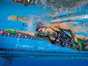 Sideview of a swimmer with swimming hand paddles