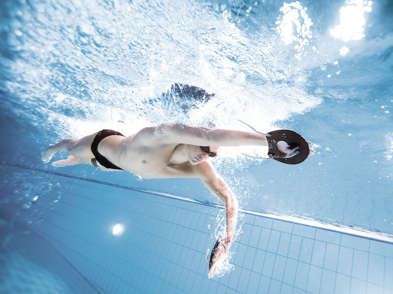 Underwater shot of a swimmer with swimming hand paddles