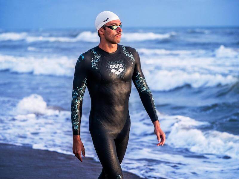 Wetsuits for swimming: swimmer walking on a beach