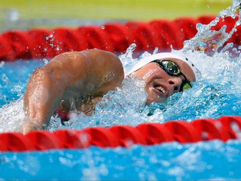 A closeup of a swimmer wearing goggles and a swim cap in the pool