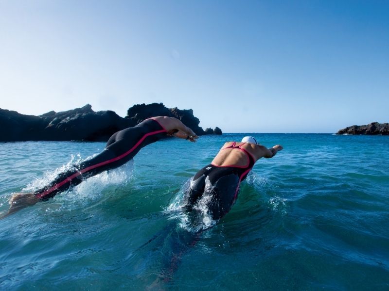 Two swimmers dive into open water