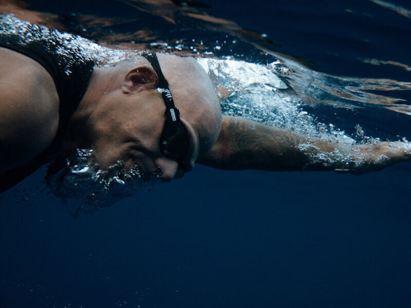 man swimming with earplugs