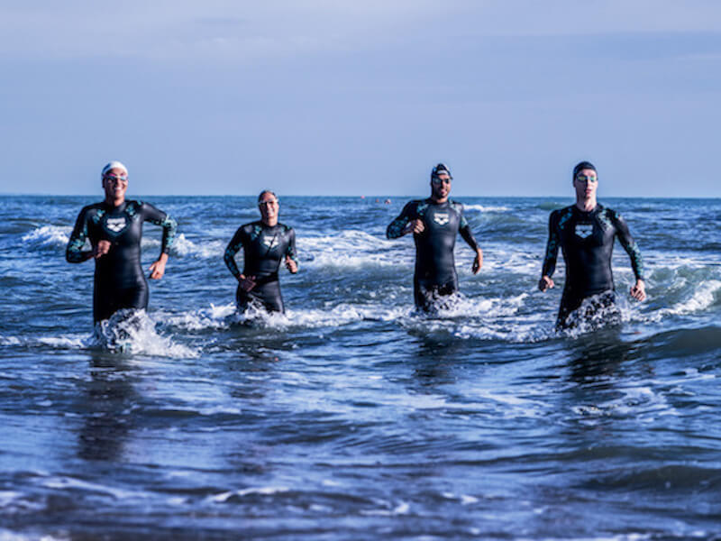 swim workout for triathlon: group of swimmers running in the water