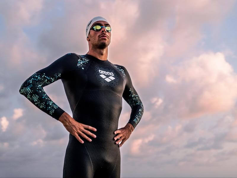 Swimmer wearing an open water swimming wetsuit standing tall and proud