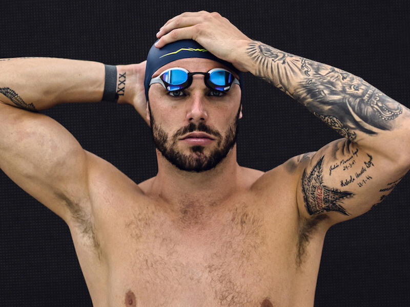 A swimmer puts on his arena swim cap and goggles