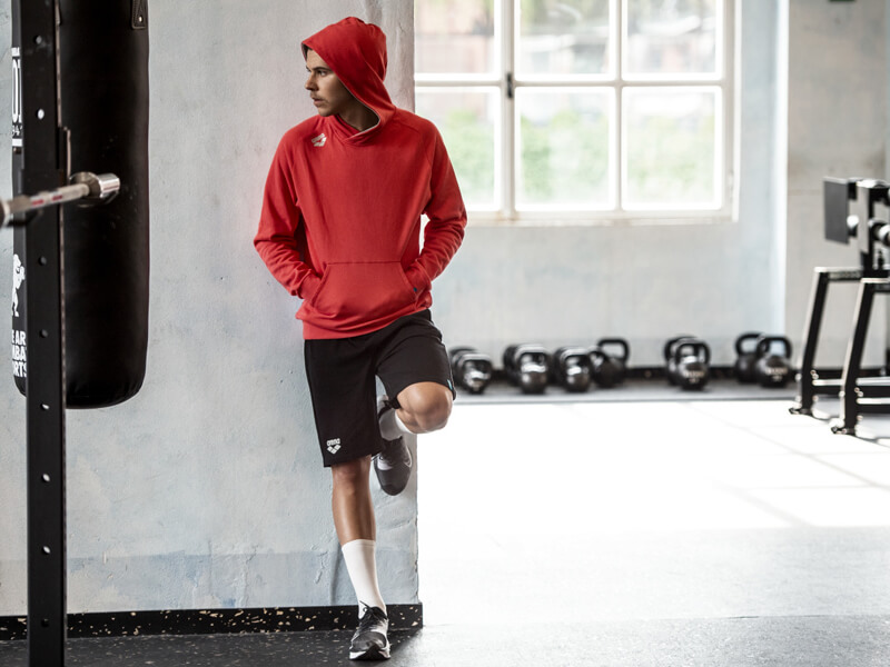 Core exercises for swimmers: man wearing a red hoodie at the gym
