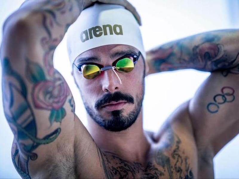 Types of swimming caps: man adjusting his Arena swimming cap