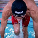Types of swimming caps: man wearing an Arena swim cap getting out of the pool
