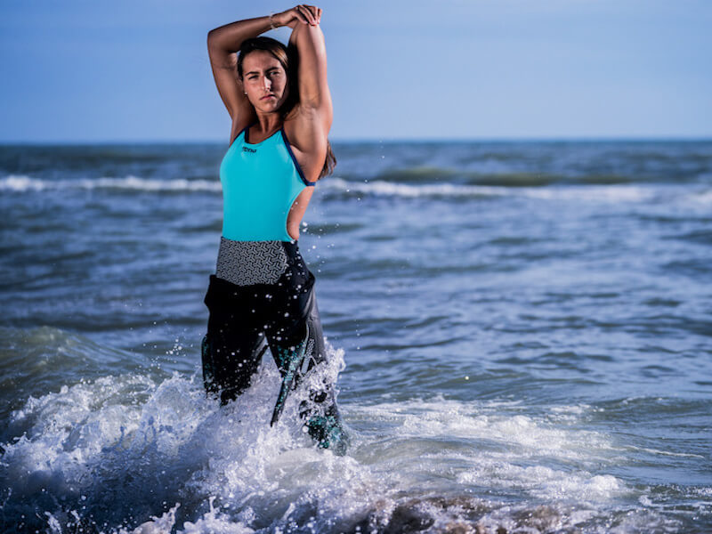 Woman stretching her arm while standing on the shore